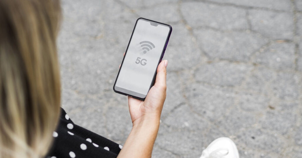 Women holding a phone with 5G service on it