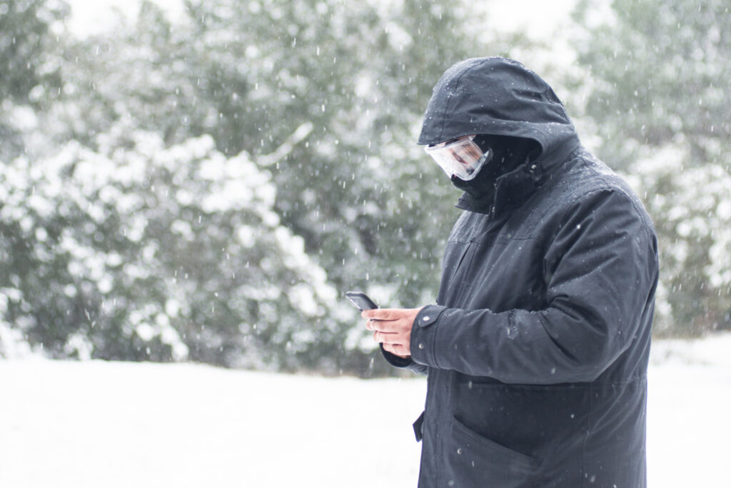 man using a cellphone in the snow