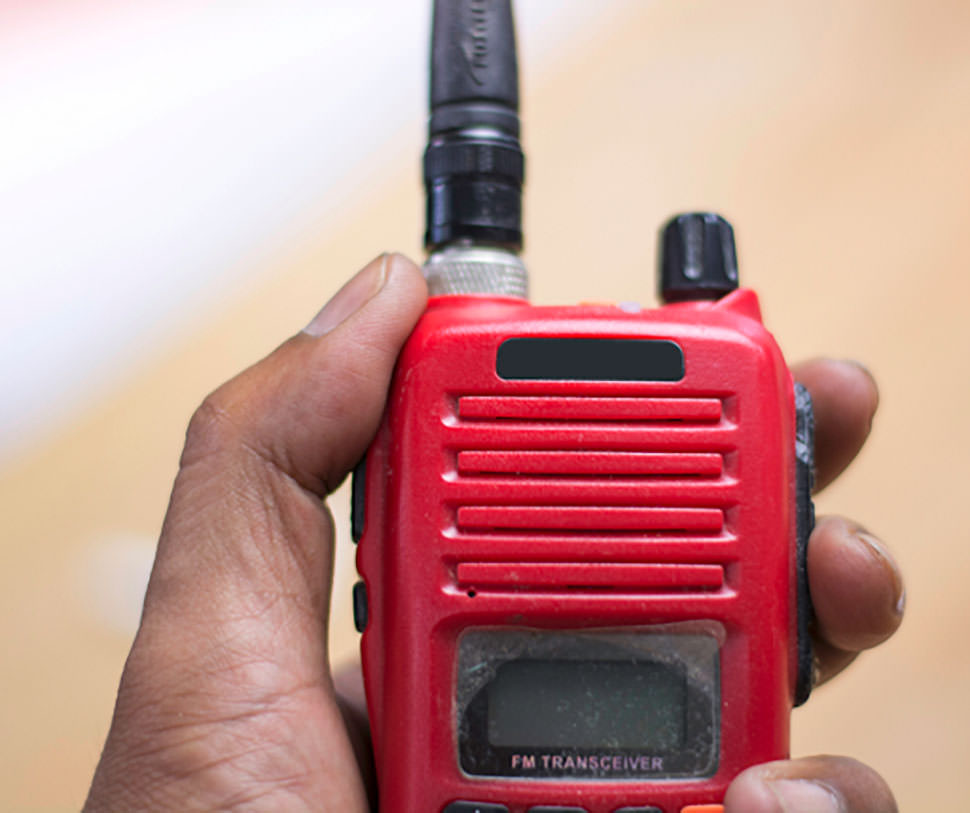 A hand holding a red two way radio